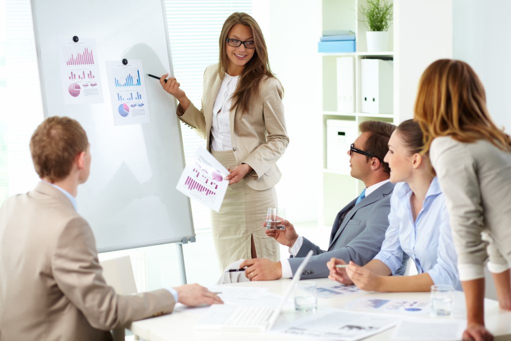Confident businesswoman commenting marketing results to colleagues at meeting